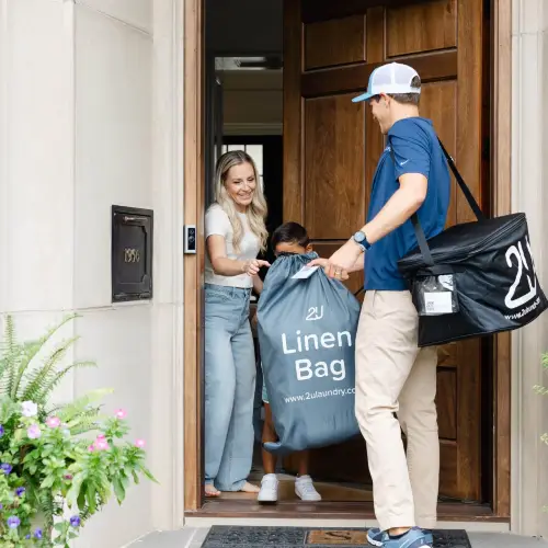A driver picking up a laundry bag from a home.